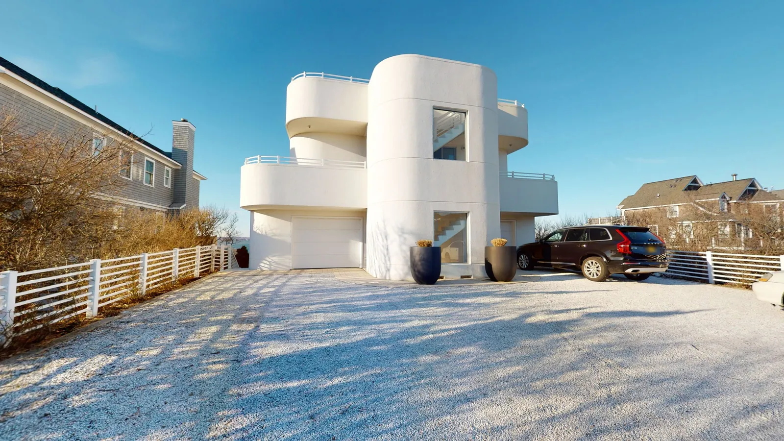 Curved white modern home with rounded balconies and a gravel drive, shown as a photograph and as a blueprint drawing